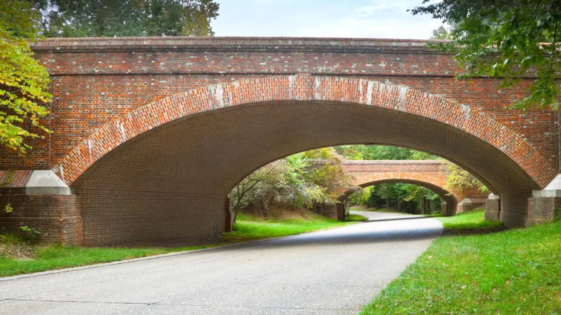 An old brick bridge spans over a road, showcasing its weathered structure and historical charm.