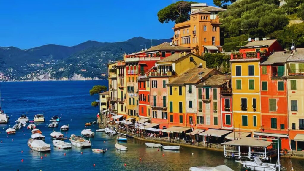 A row of brightly colored buildings lines the shore of a tranquil bay, reflecting a lively coastal atmosphere.