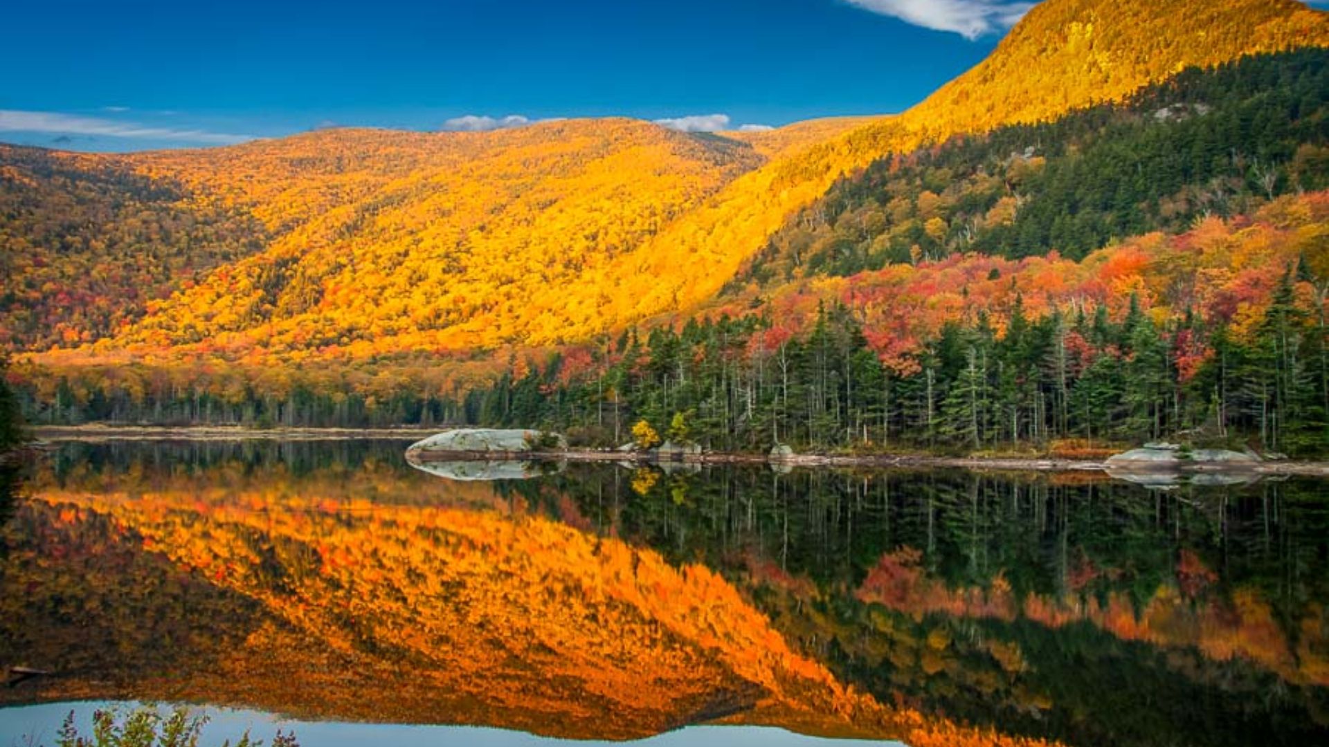 Autumn landscape reflecting vibrant colors in still water, captured by photographer Jimmy Kirk.
