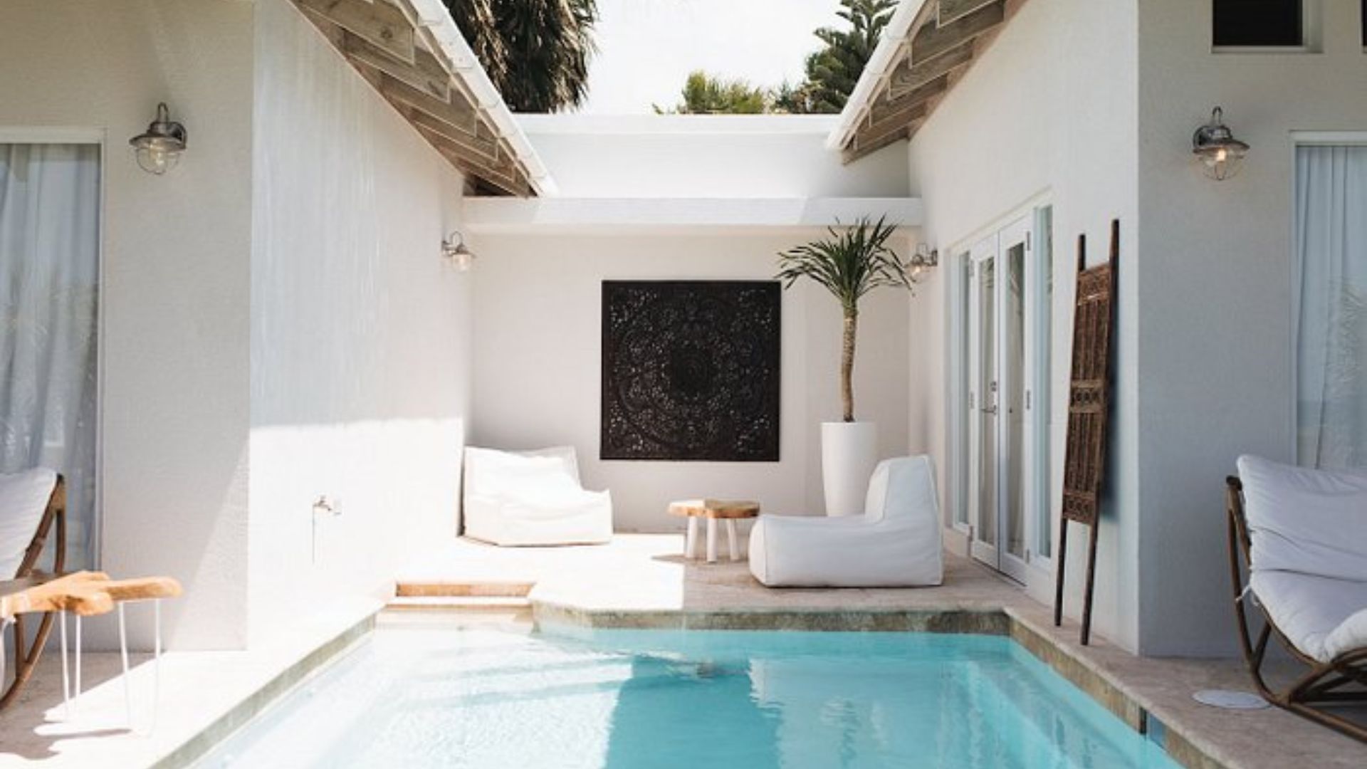 A serene pool surrounded by lounge chairs in a modern white house setting.