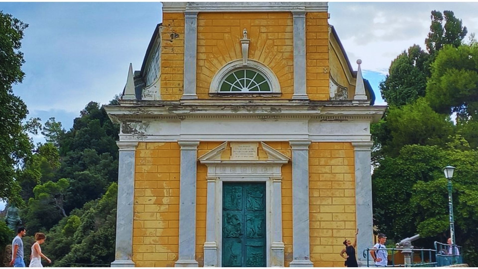 A charming yellow church with a distinctive green door, showcasing a welcoming appearance.