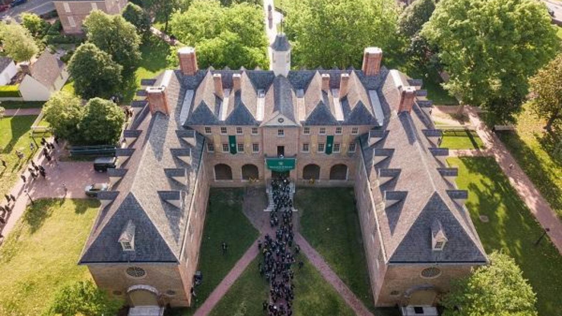 . Aerial view of a large brick building, showcasing its front facade and surrounding landscape.