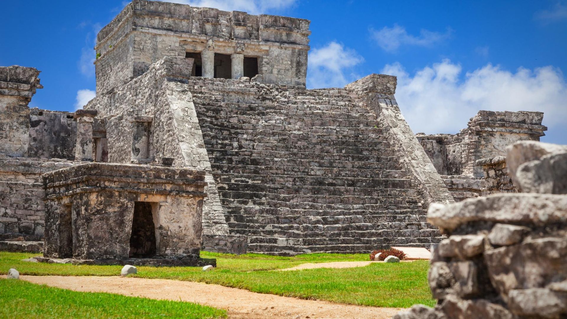 Ruins of an ancient Mayan city in Mexico, showcasing stone structures and lush greenery surrounding the archaeological site.