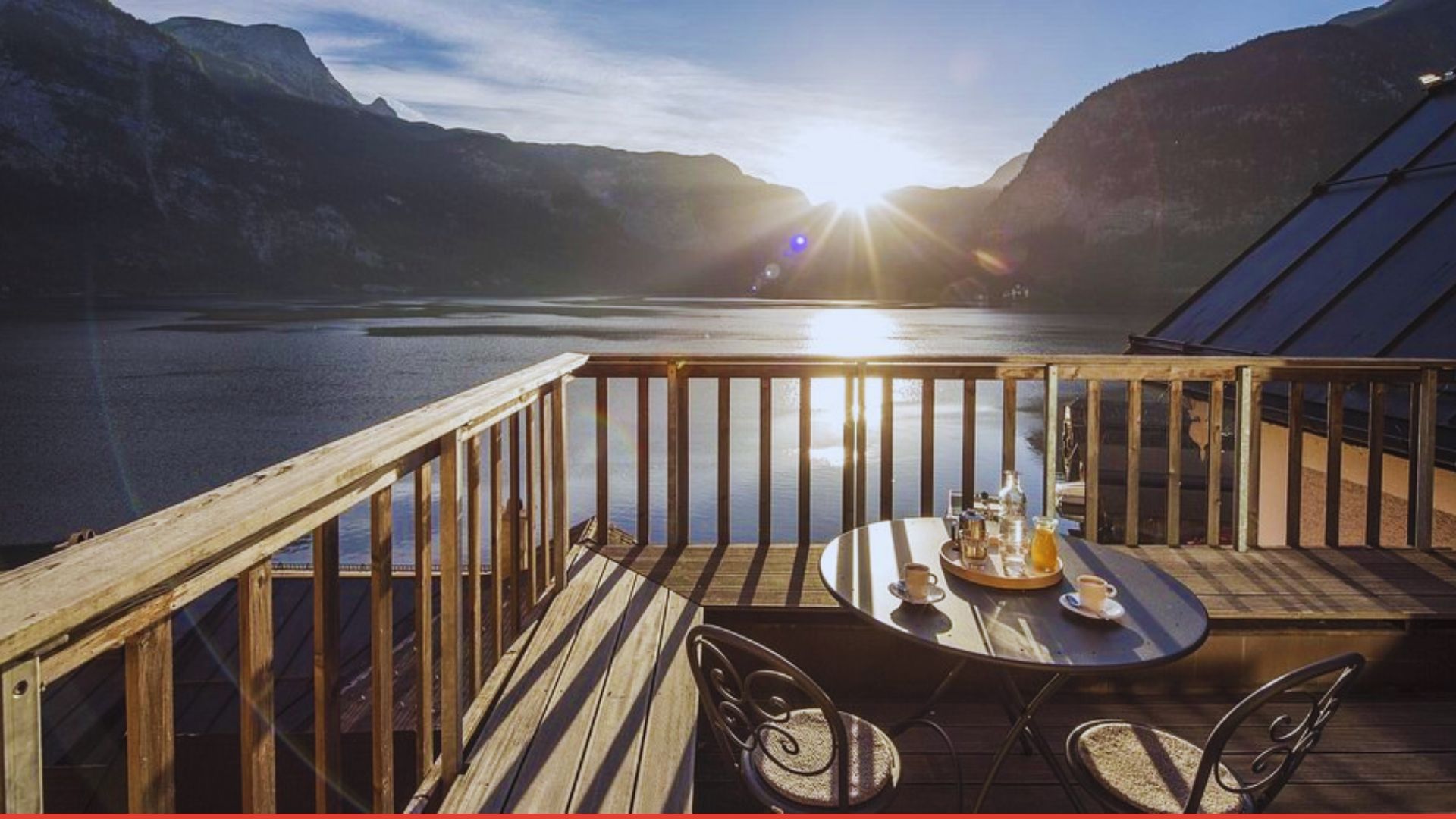 Sunlight illuminates a balcony featuring a table and chairs, creating a warm and inviting outdoor space.