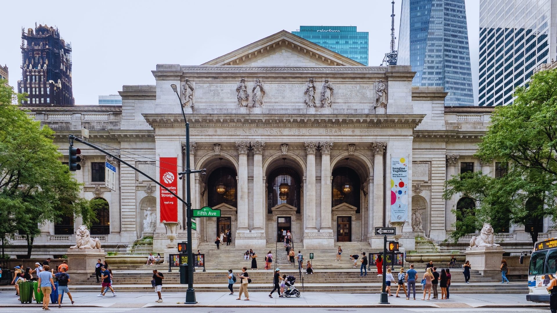 Individuals walk by a monumental building with towering columns, emphasizing its architectural significance.