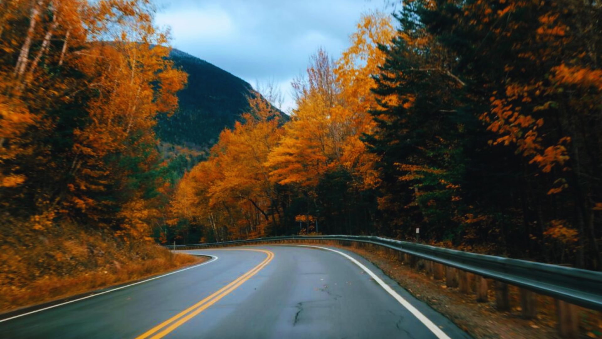 A picturesque mountain road surrounded by vibrant autumn leaves, inviting travelers to explore the landscape.