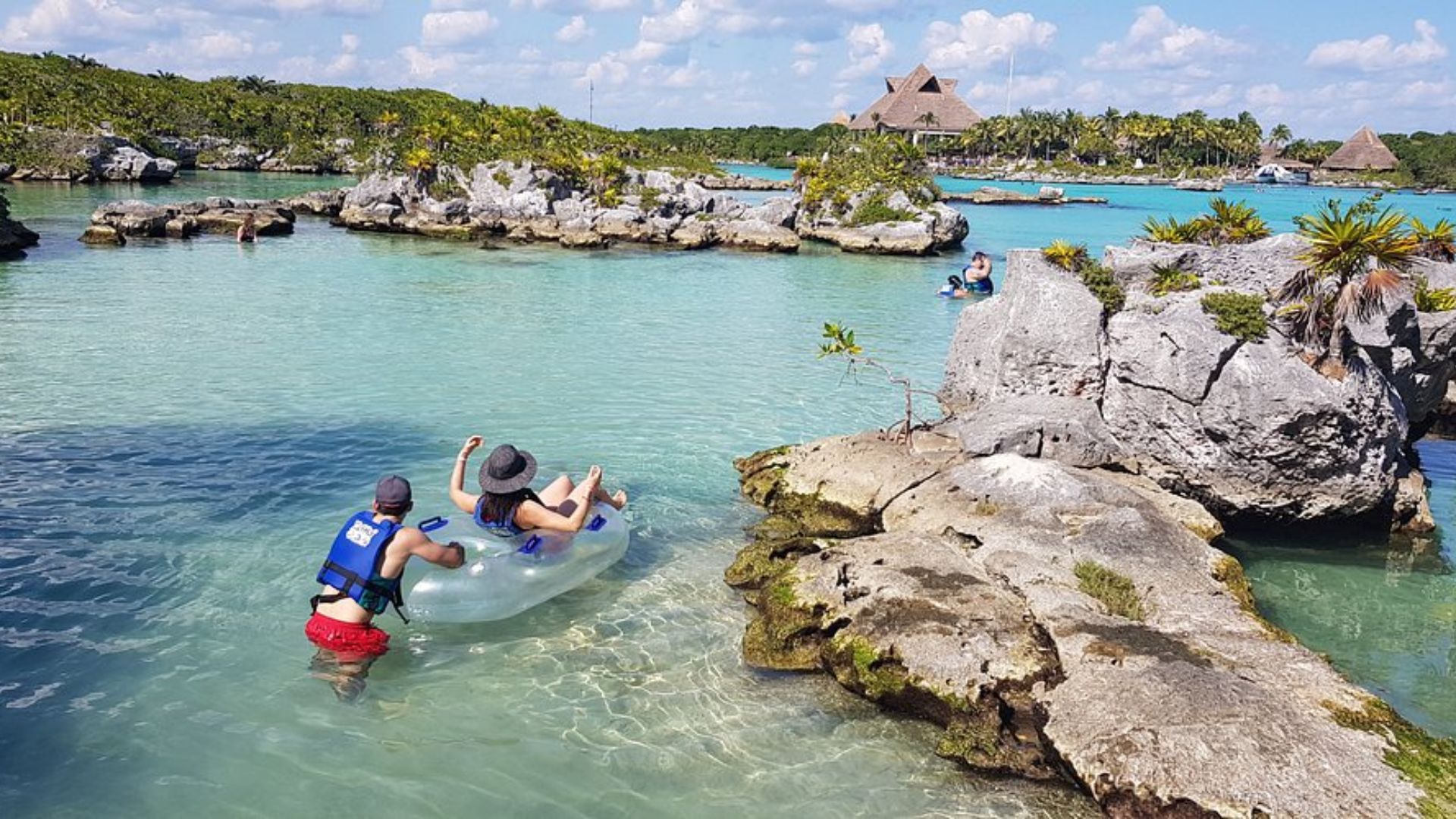 A group of people enjoying a leisurely float in an inflatable raft on calm water under a clear sky.