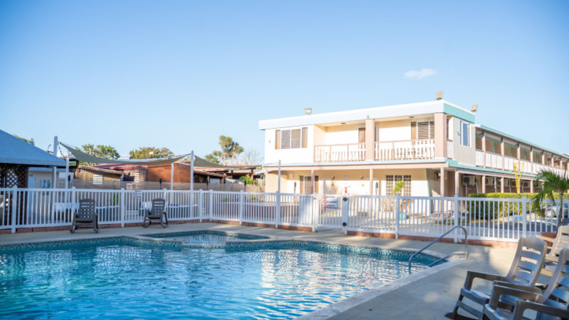 A motel featuring a pool with lounge chairs positioned in front, inviting relaxation and leisure.