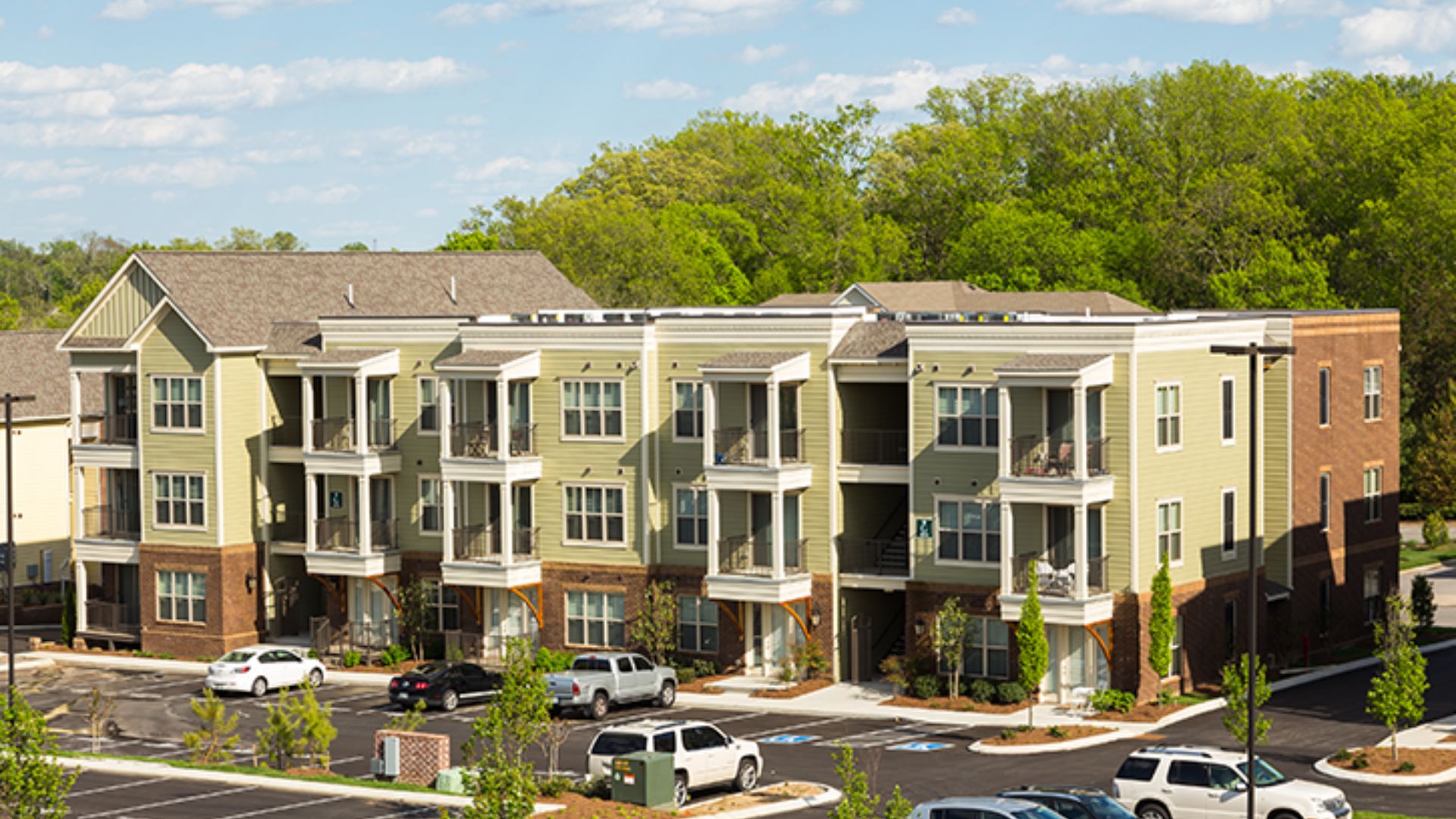 A large apartment complex with multiple floors and a spacious parking lot in front.