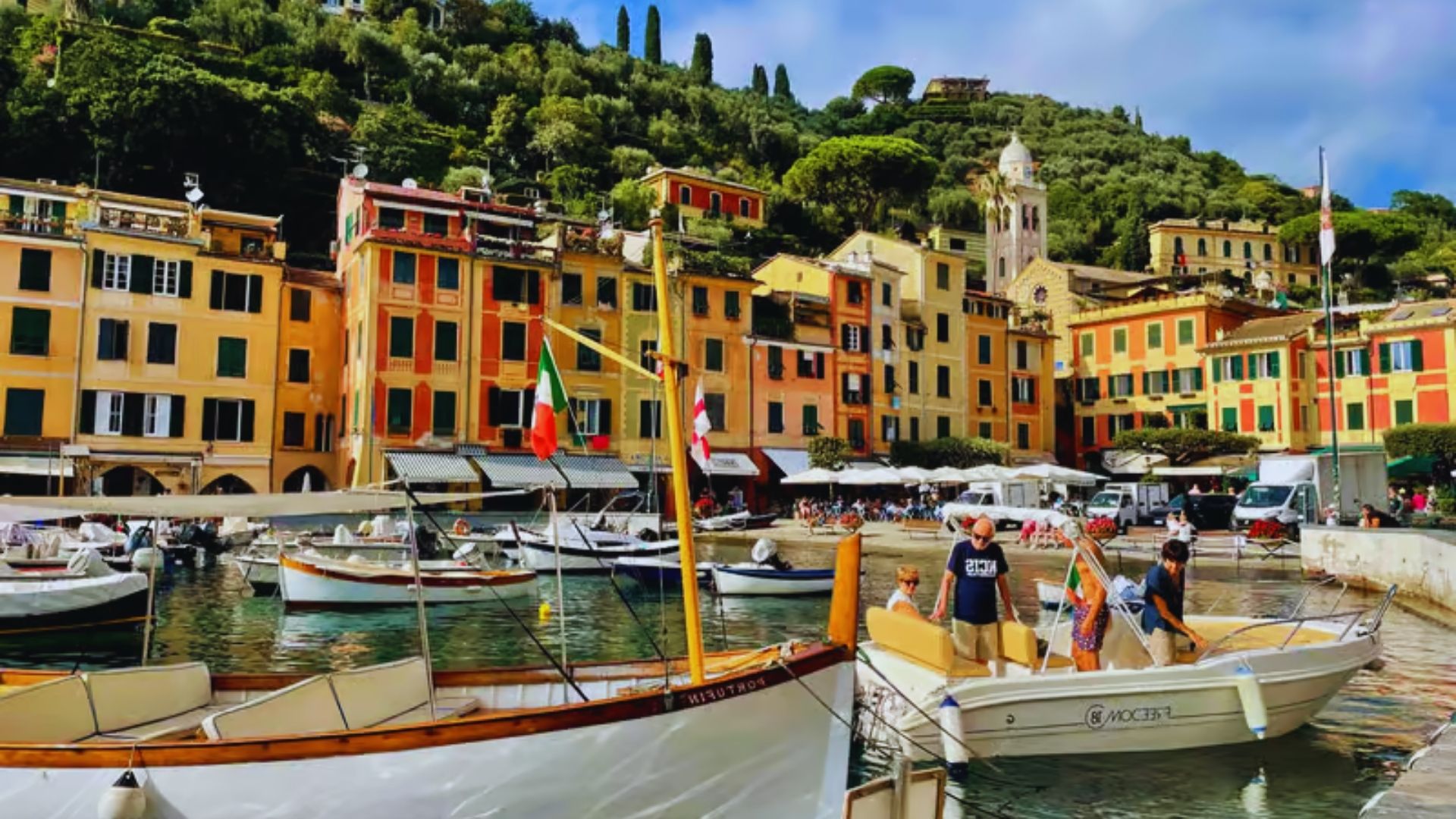 Scenic view of Portofino, Italy, showcasing colorful buildings along the waterfront and lush green hills in the background.