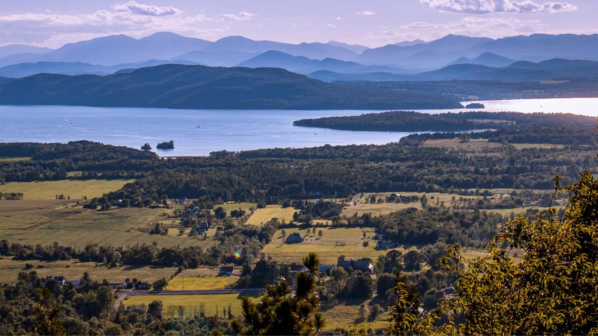 A panoramic view of mountains and a serene lake from a high vantage point, showcasing natural beauty and tranquility.