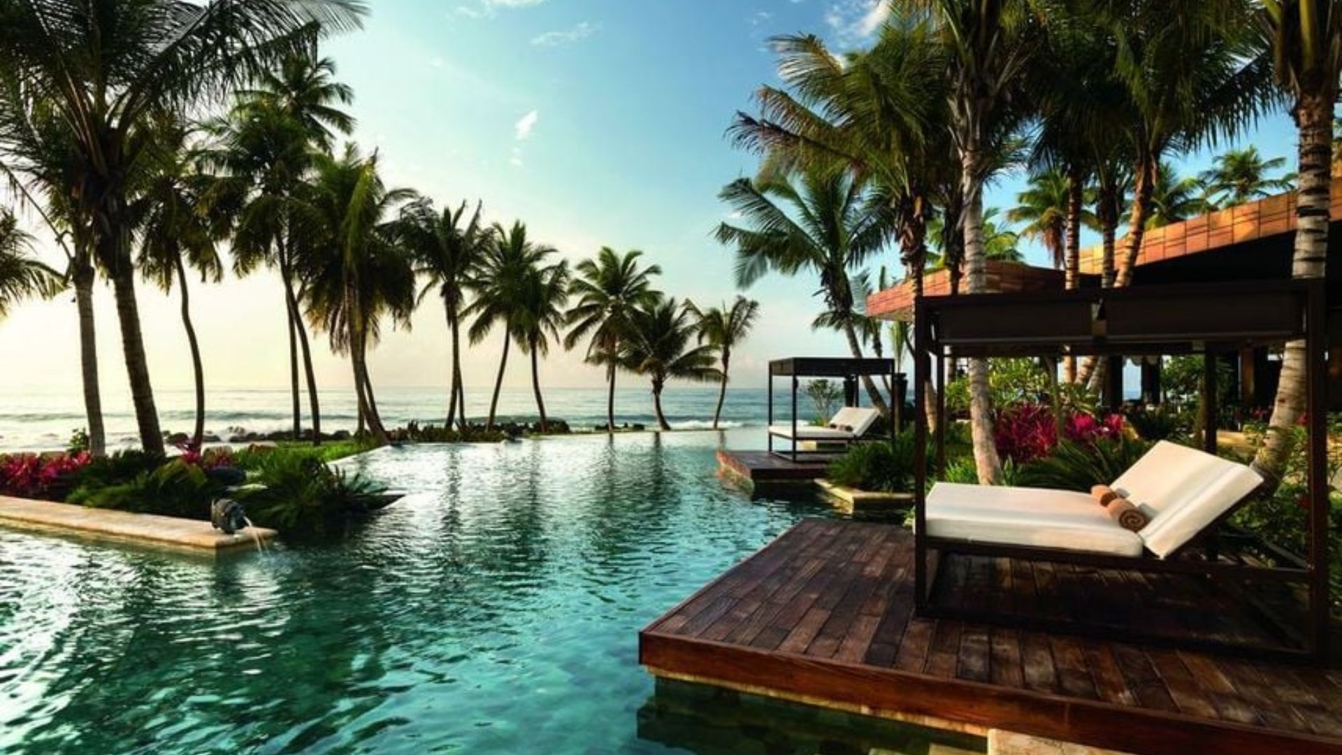 A serene pool surrounded by lounge chairs and palm trees, creating a relaxing tropical atmosphere.
