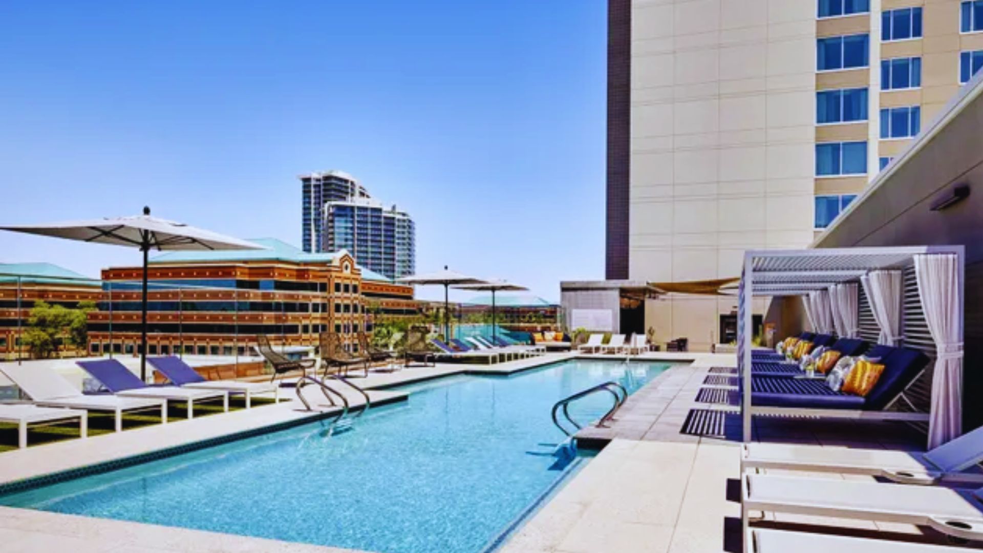 The Hilton Houston Hotel's inviting pool, complete with sun loungers and lush greenery, perfect for relaxation.