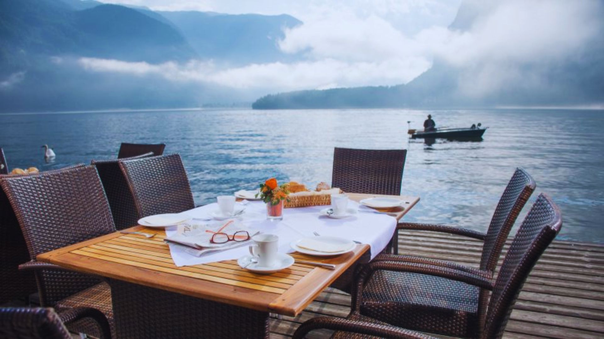 A table elegantly set for breakfast, featuring a view of calm waters in the background.