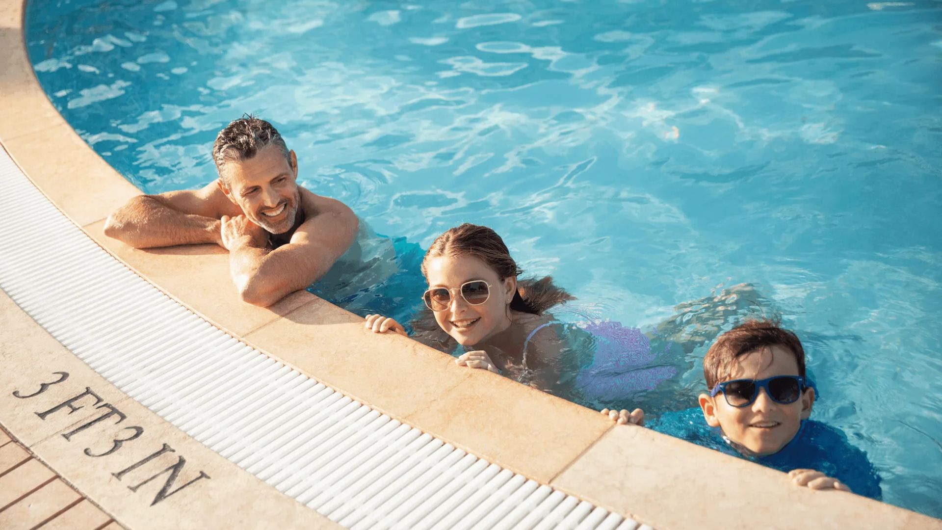 Three individuals are swimming in a pool, featuring the letters "nf" on its edge.