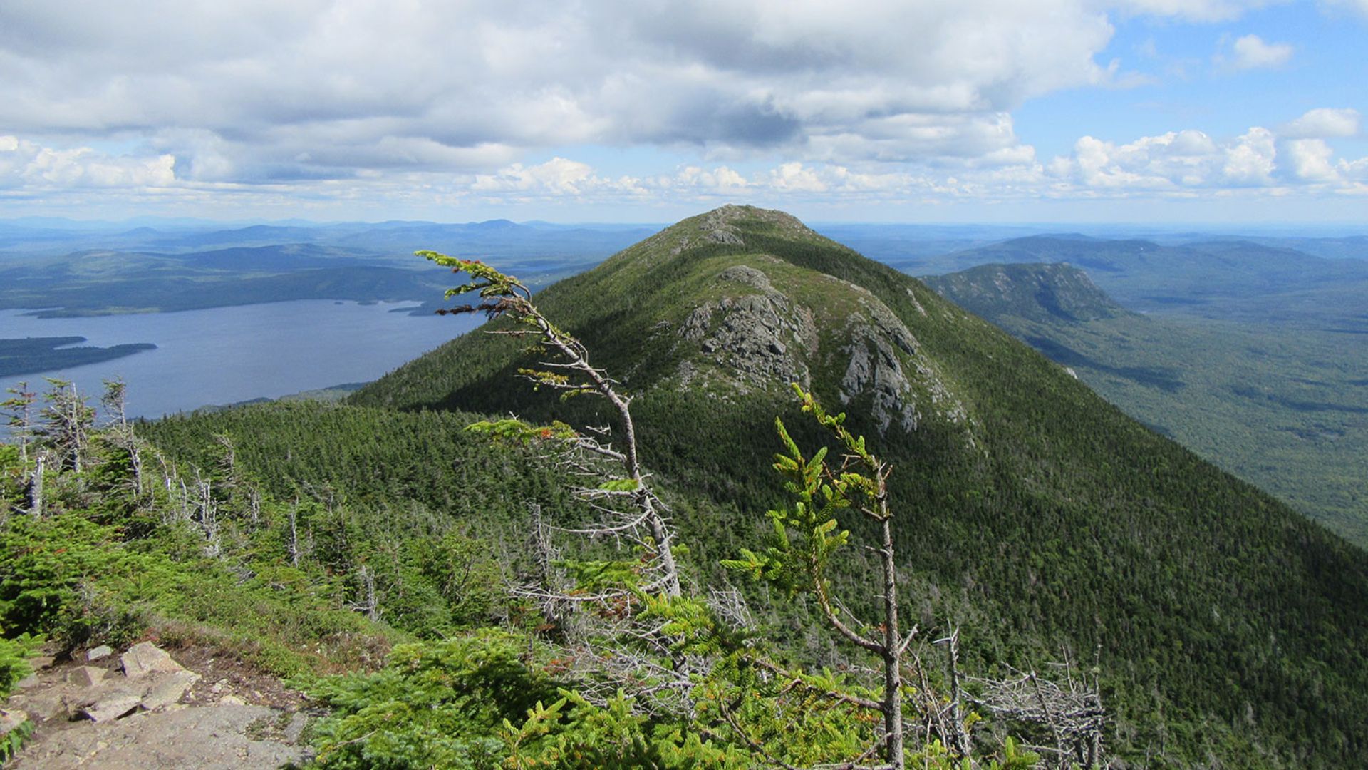 A majestic mountain rises in the background, with a serene lake reflecting its beauty in the foreground.