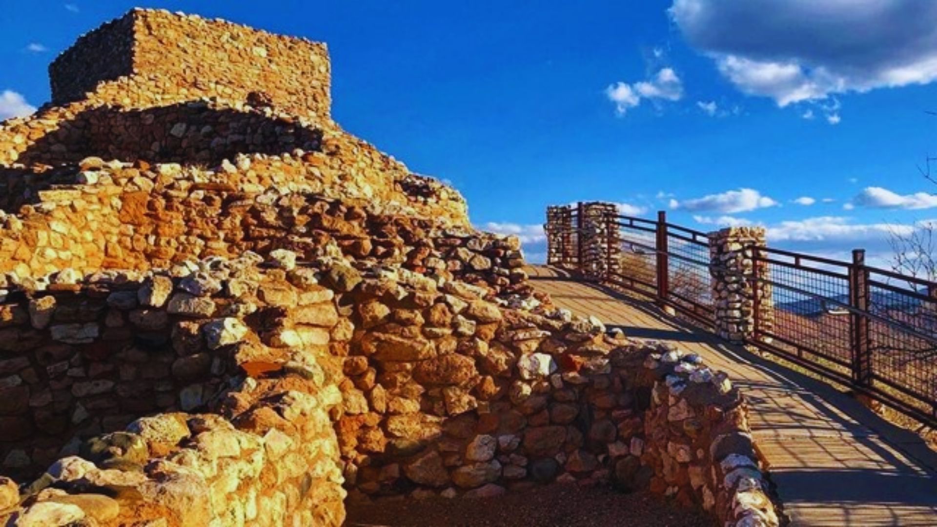 Ancient Maya city ruins in Mexico, featuring crumbling stone buildings and overgrown vegetation in the background.