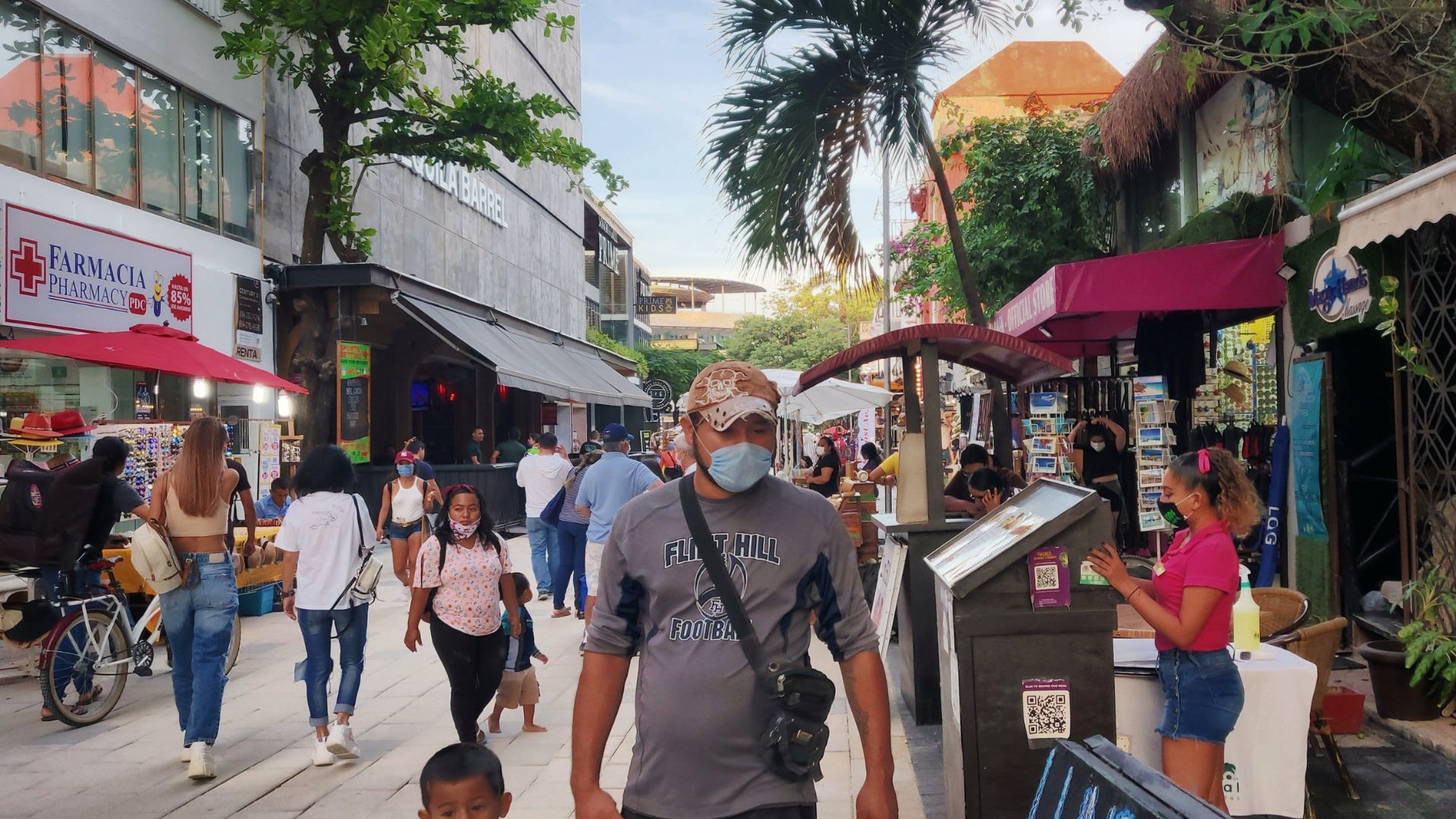 A busy street scene with people walking among shops and storefronts, creating a lively urban atmosphere.