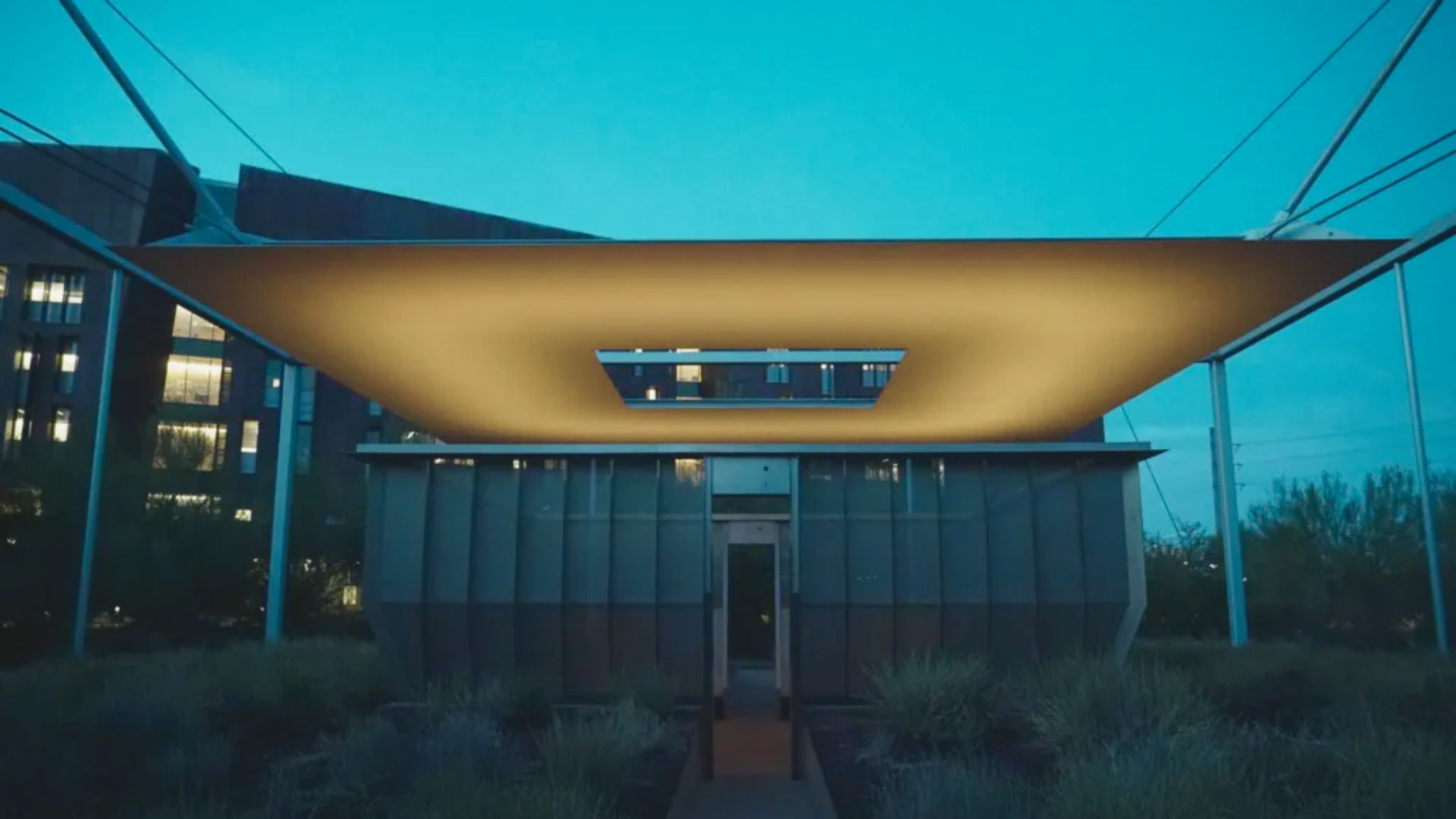 A building illuminated by a bright light above it, highlighting its architectural features against the night sky.
