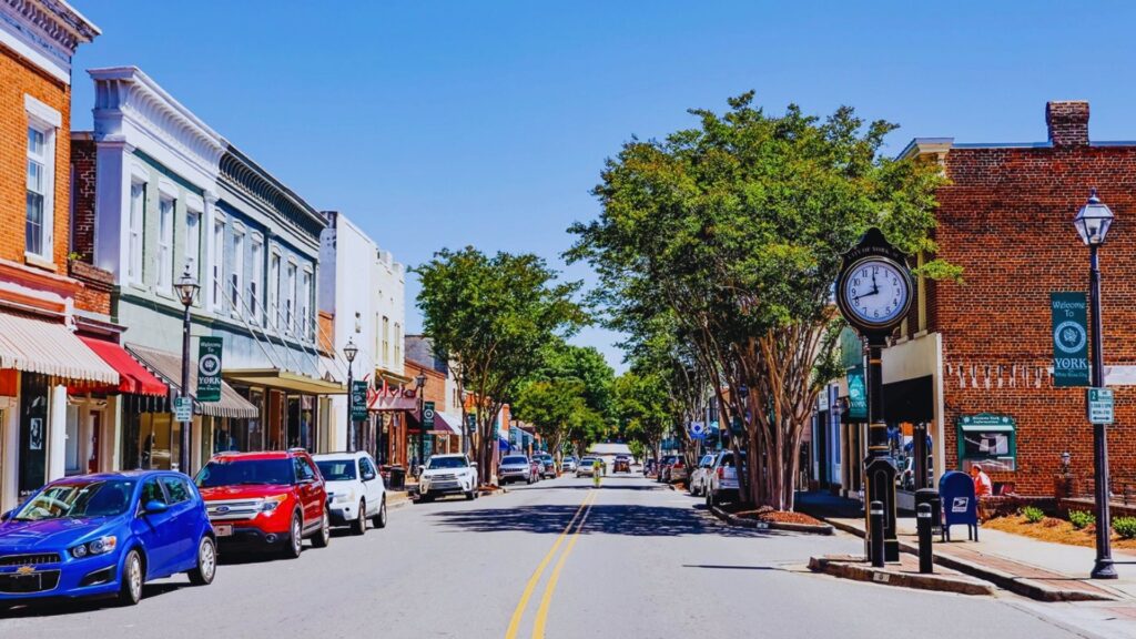 A city street lined with parked cars on both sides, showcasing urban life and traffic patterns.