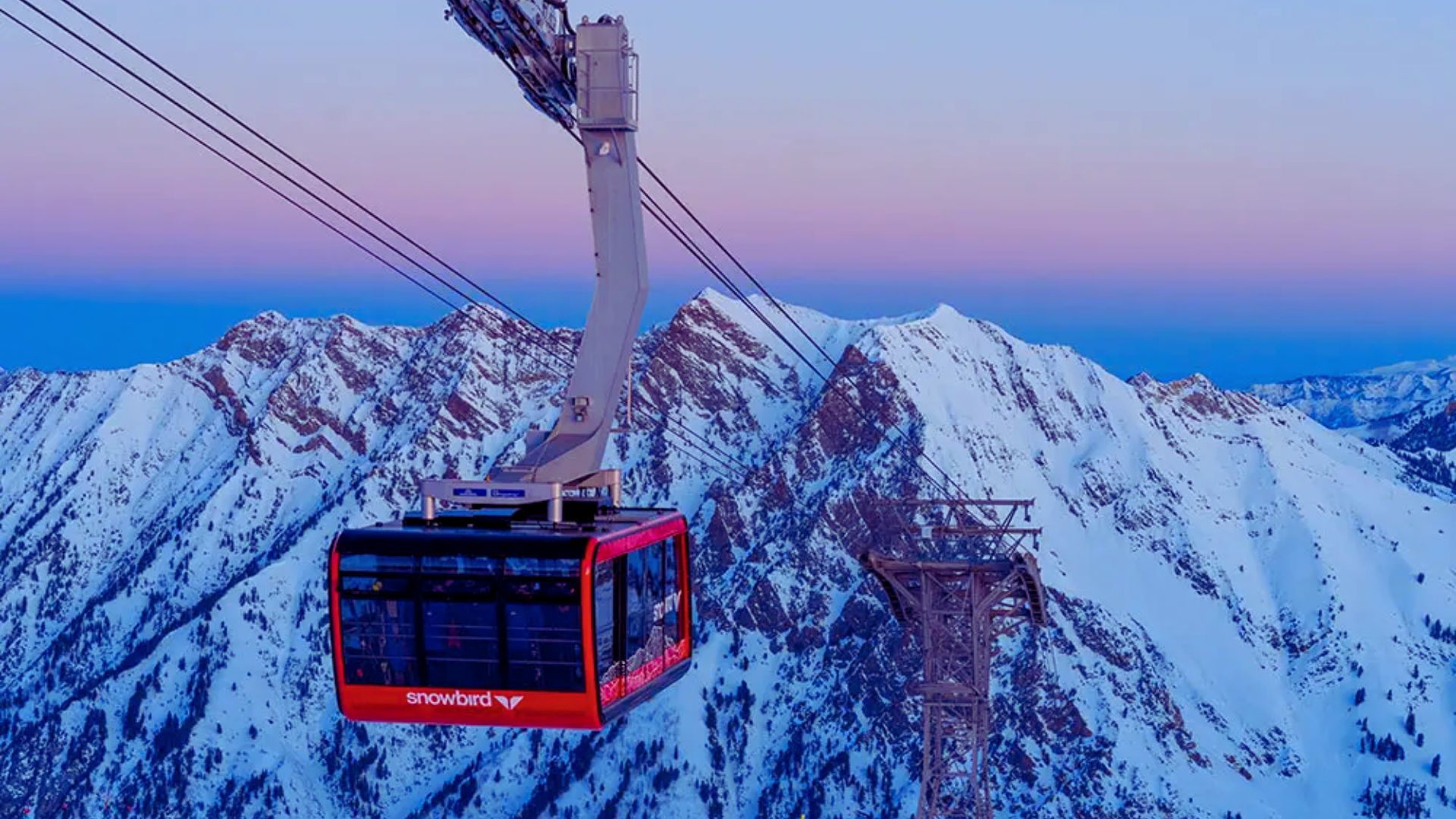 A gondola glides above snow-covered mountains, showcasing a stunning winter landscape.