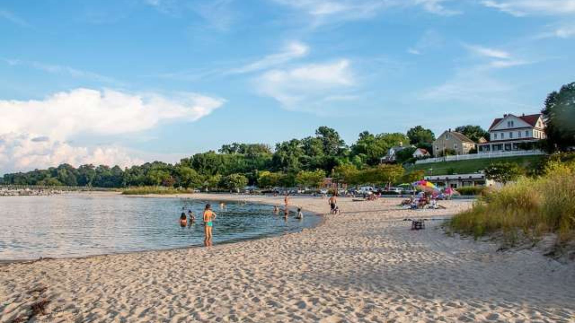 A scenic beach view adjacent to the hotel, featuring soft sand and gentle waves under a clear blue sky.