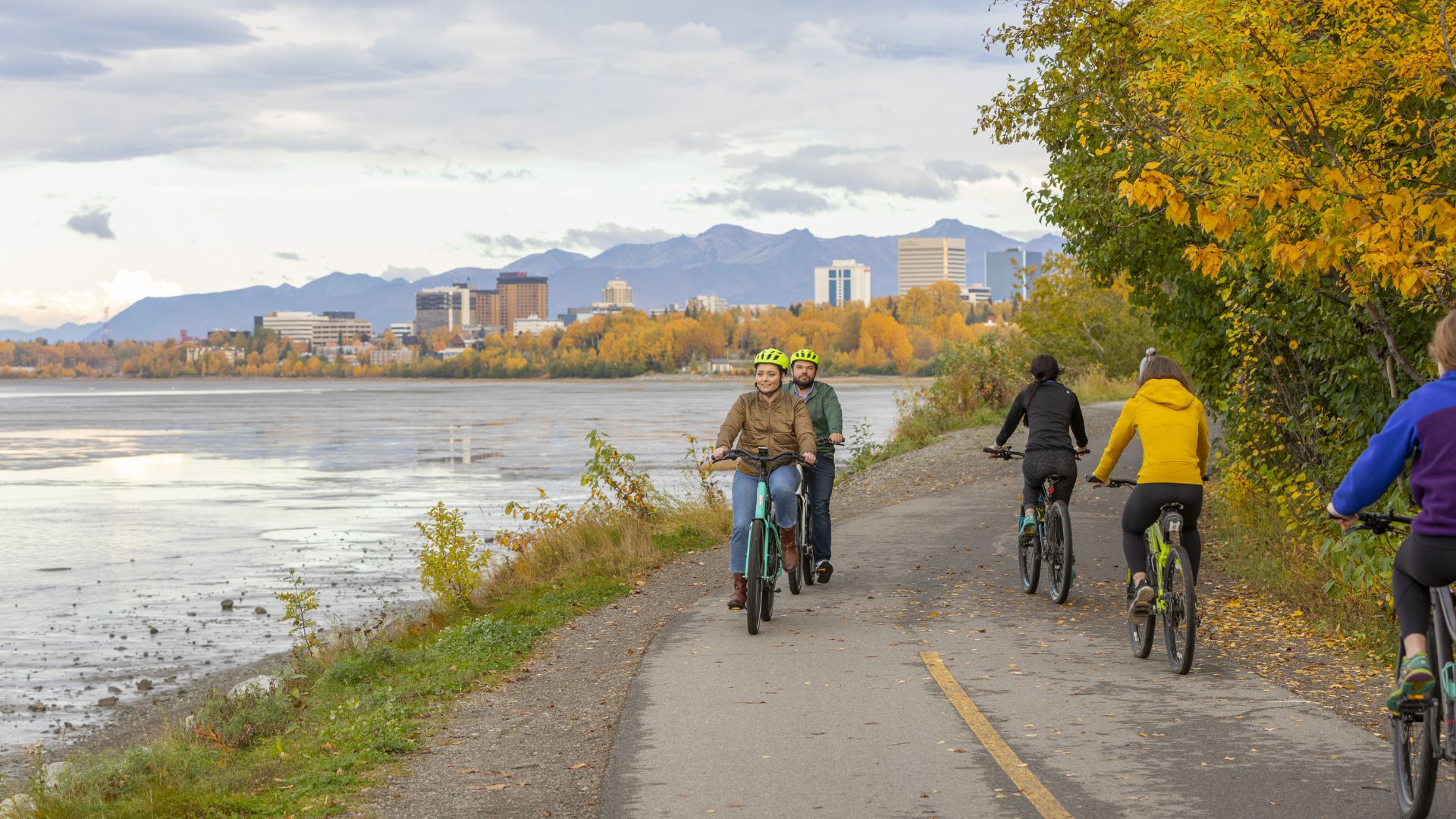 A diverse group of people riding bicycles along a scenic path on a sunny day.