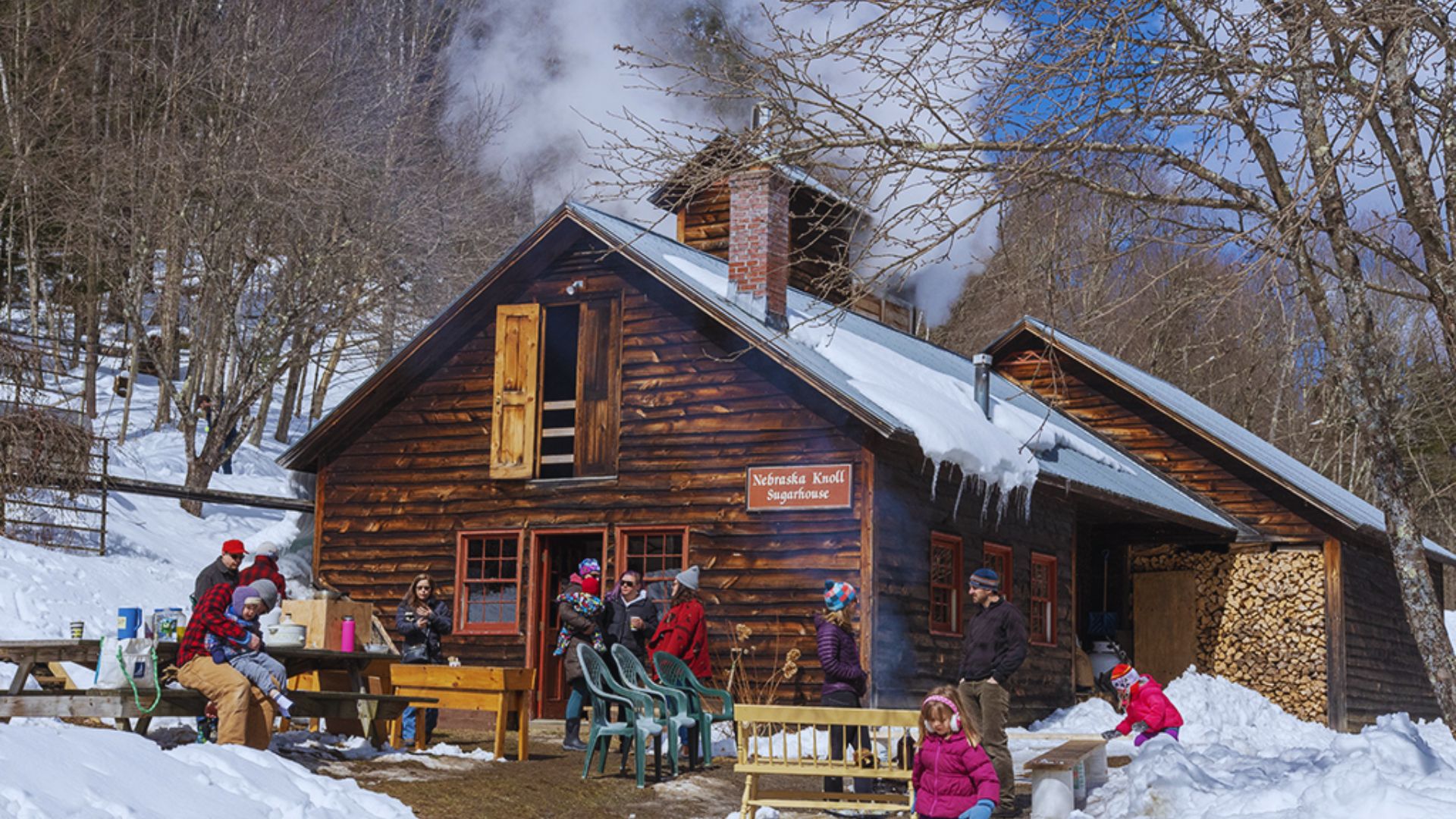 A group of people sitting together outside a rustic cabin, enjoying the outdoors and each other's company.