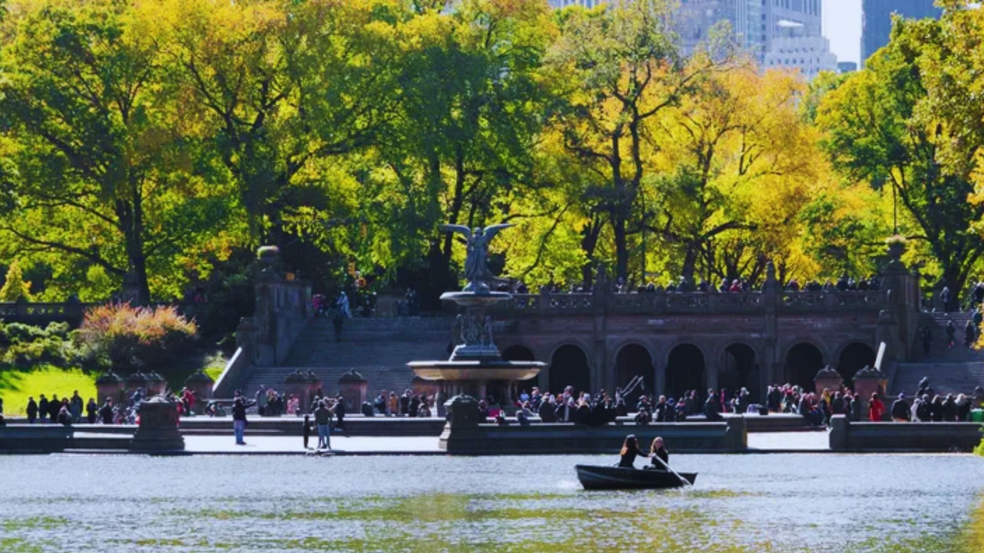 A group of individuals relaxes in a boat on Central Park's lake, enjoying the tranquil water and scenic surroundings.