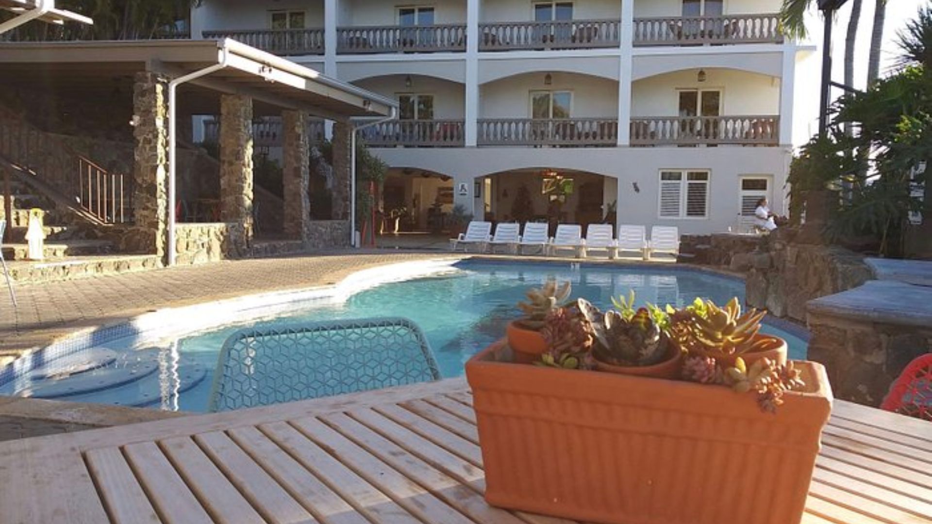 A pool with a table and chairs is situated in front of a building, creating a relaxing outdoor space.