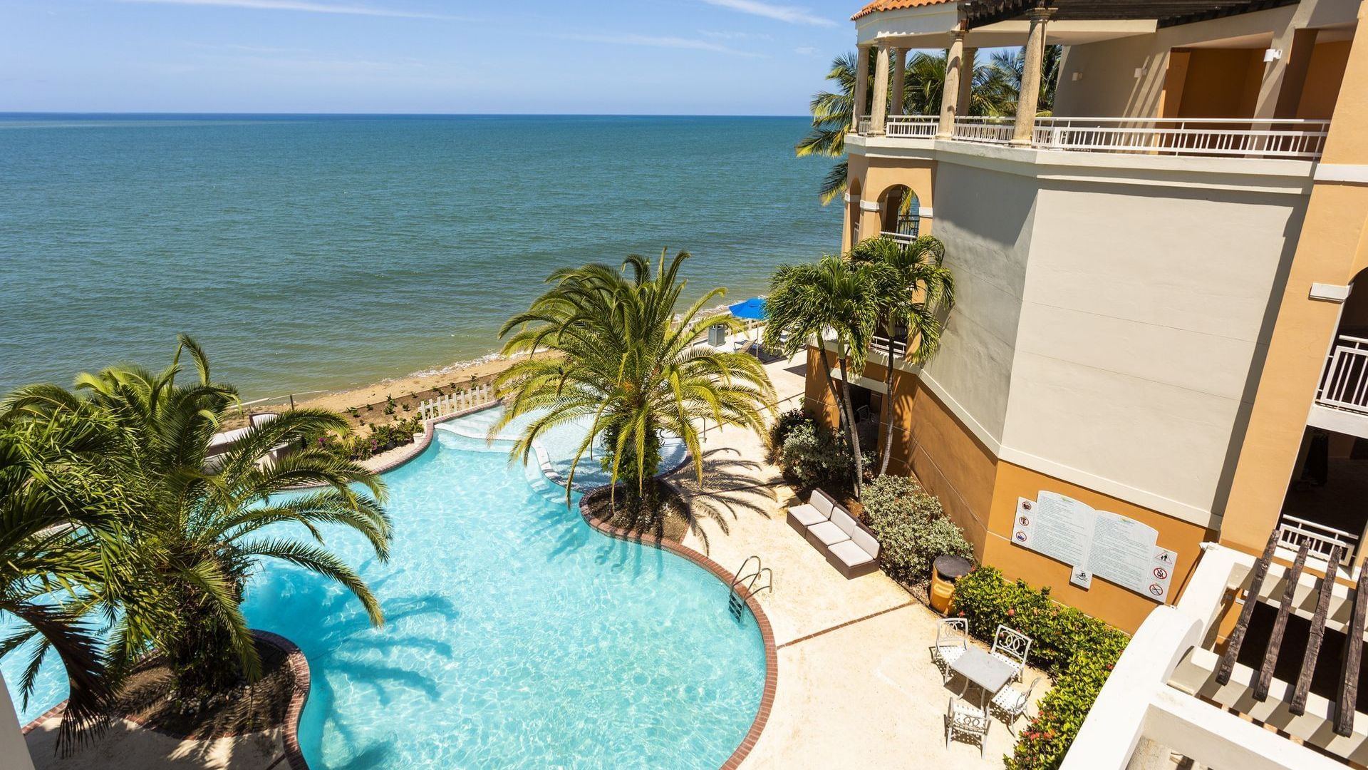 A scenic view of the ocean from a balcony, showcasing waves and a clear blue sky.
