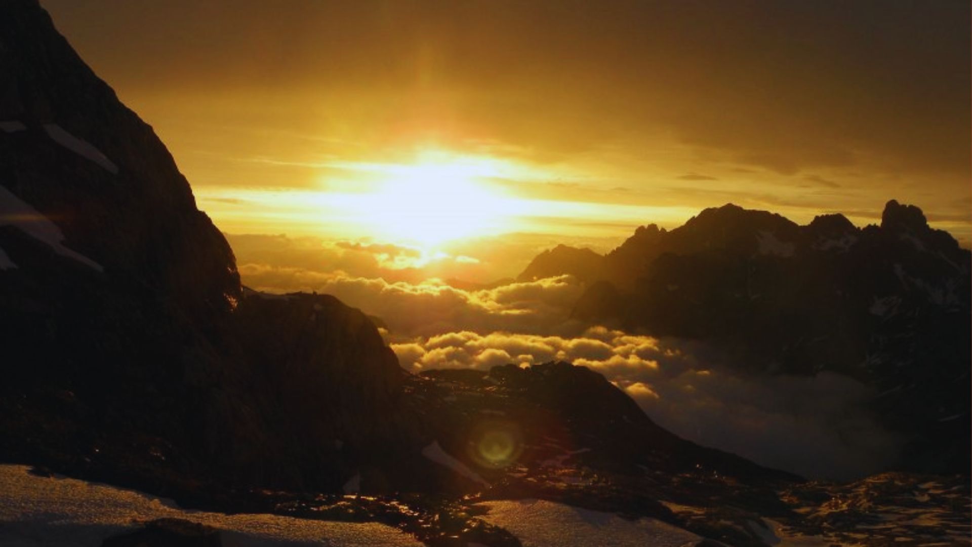 A vibrant sunset casts warm hues over majestic mountains, creating a serene and picturesque landscape.