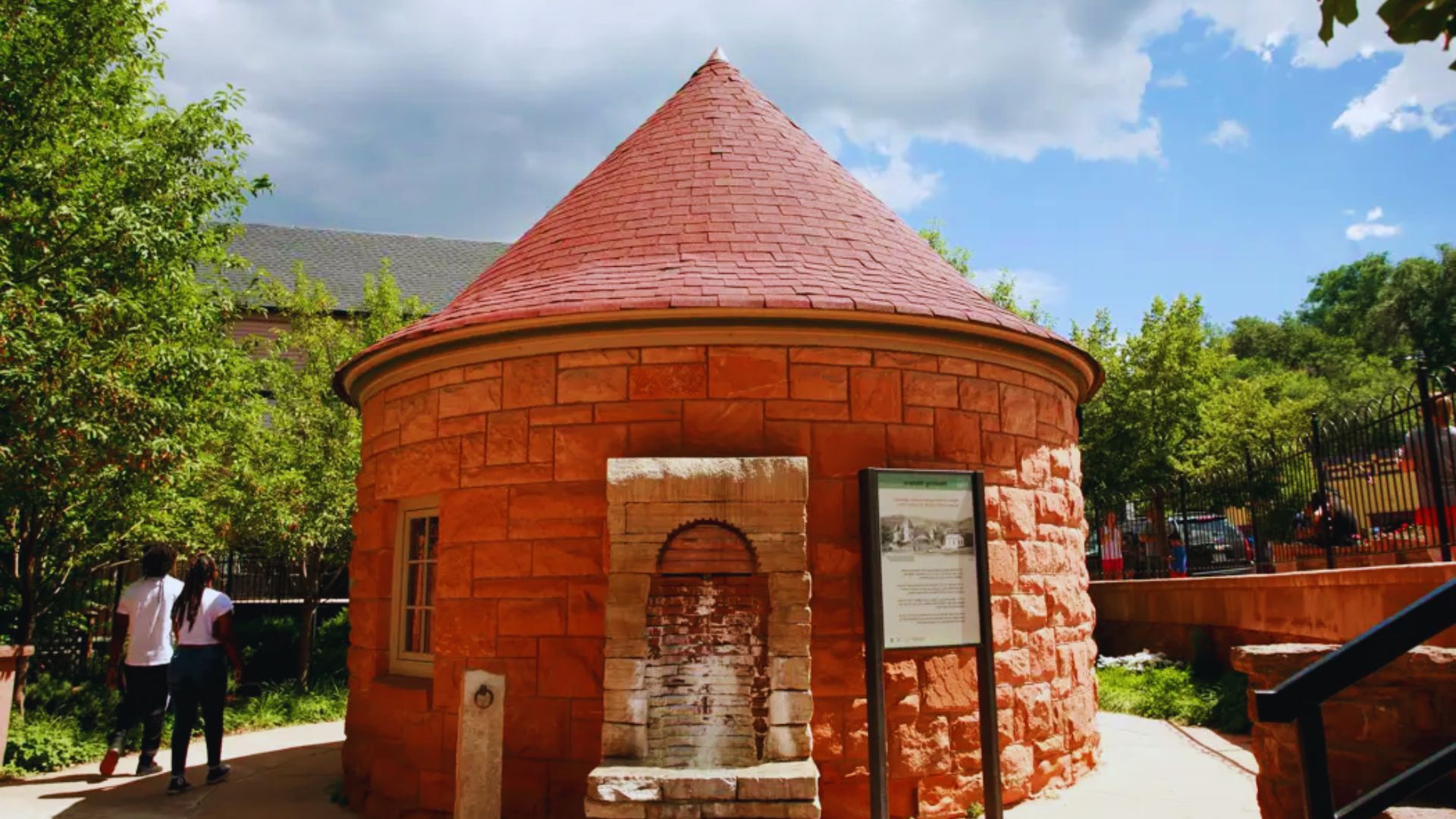 A water fountain in front of a red brick building, showcasing a blend of nature and architecture.