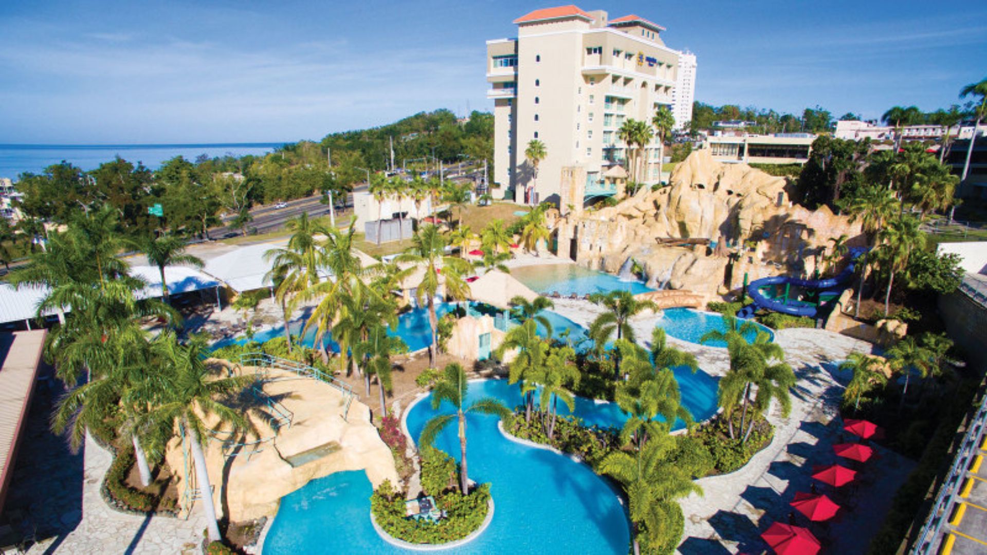 A scenic resort showcasing a swimming pool with colorful water slides, surrounded by lush greenery.