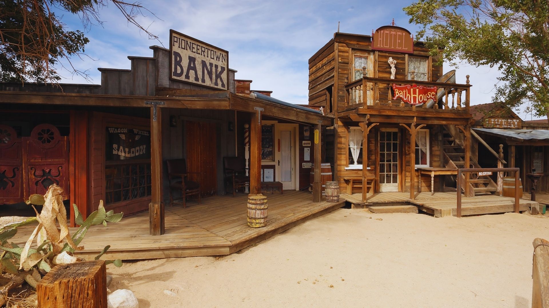 An old western town featuring a wooden building with a rustic sign hanging above the entrance.