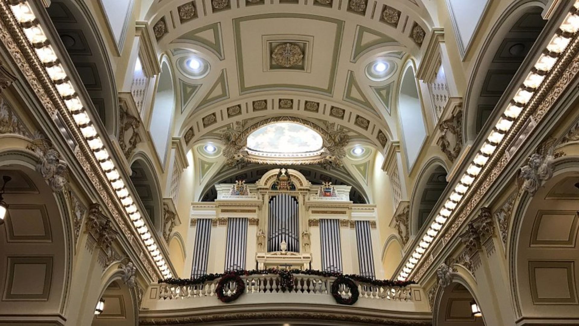 Interior of a church featuring a large, ornate organ prominently displayed in the background.