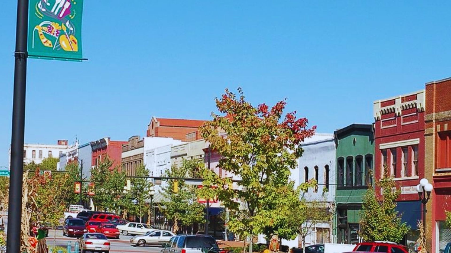 A city street lined with parked cars on both sides, showcasing urban life and traffic flow.
