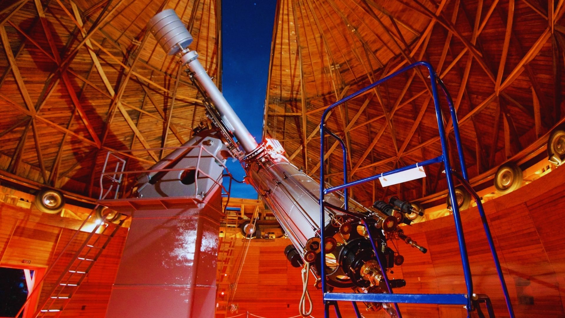 Inside a building, a large telescope stands prominently, highlighting its significance for astronomical observation.