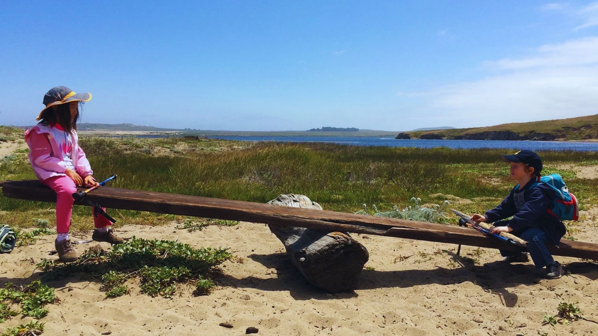 Two children happily playing on a seesaw in a sunny playground, enjoying their time together.