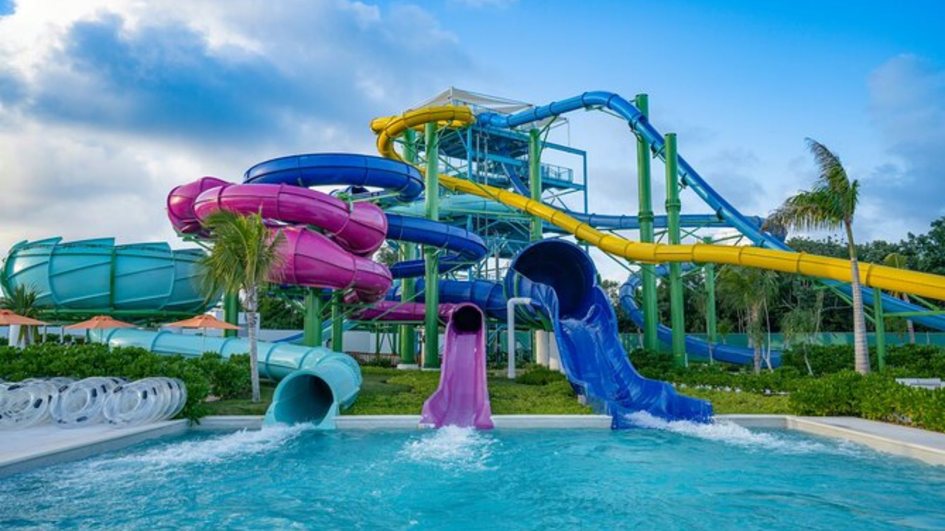 A lively water park scene showcasing bright, twisting water slides surrounded by splashing water and happy visitors.