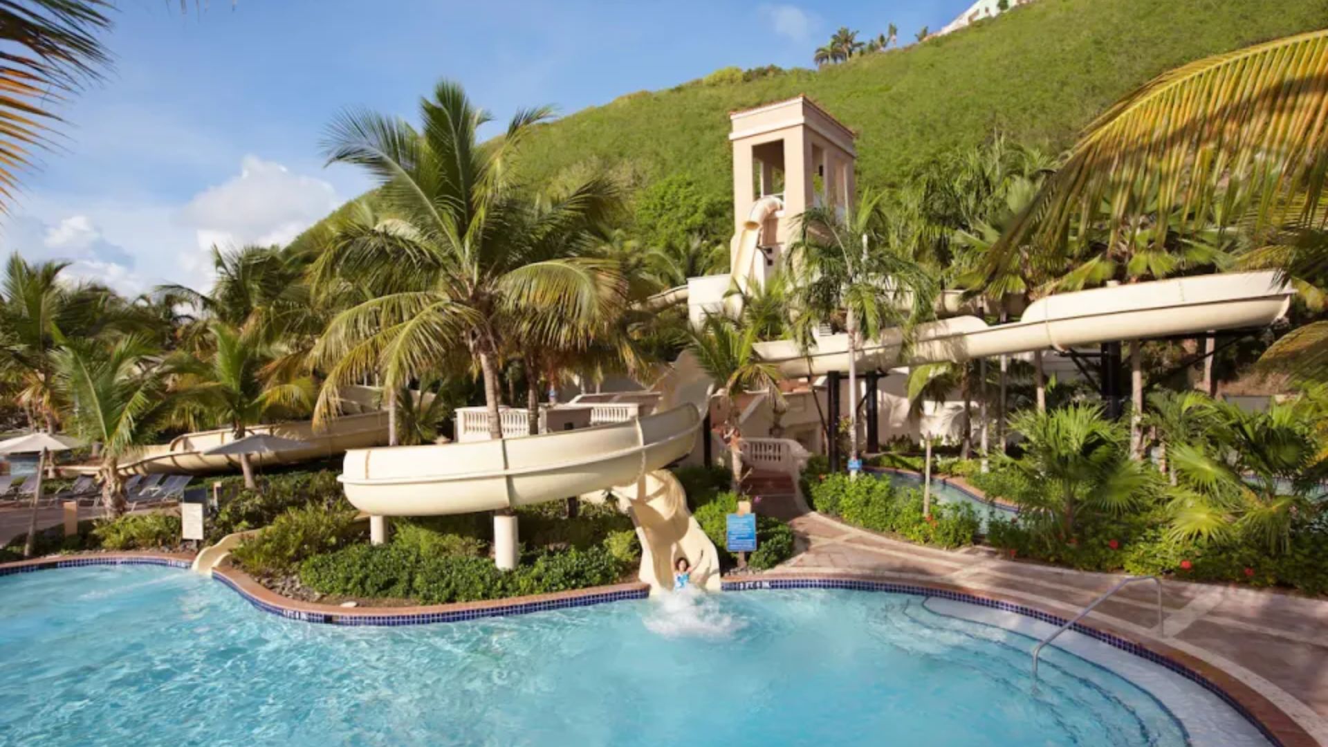 The serene pool at St. Kitts Resort & Spa, surrounded by lush greenery and sun loungers, inviting relaxation.