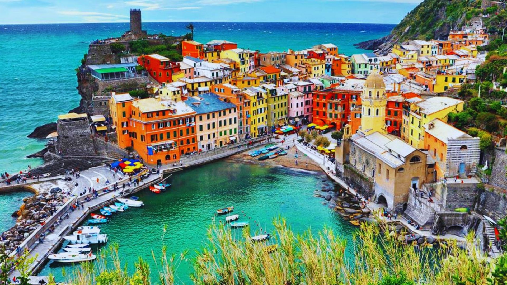 Colorful houses lining the Italian coast, showcasing vibrant architecture against a backdrop of blue sea and sky.