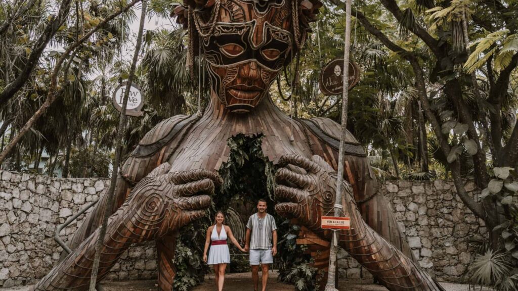 A couple stands together in front of a large statue, smiling and enjoying the view.