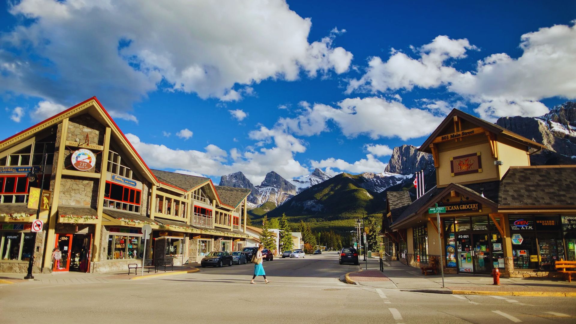 A picturesque town featuring shops with majestic mountains rising in the background.