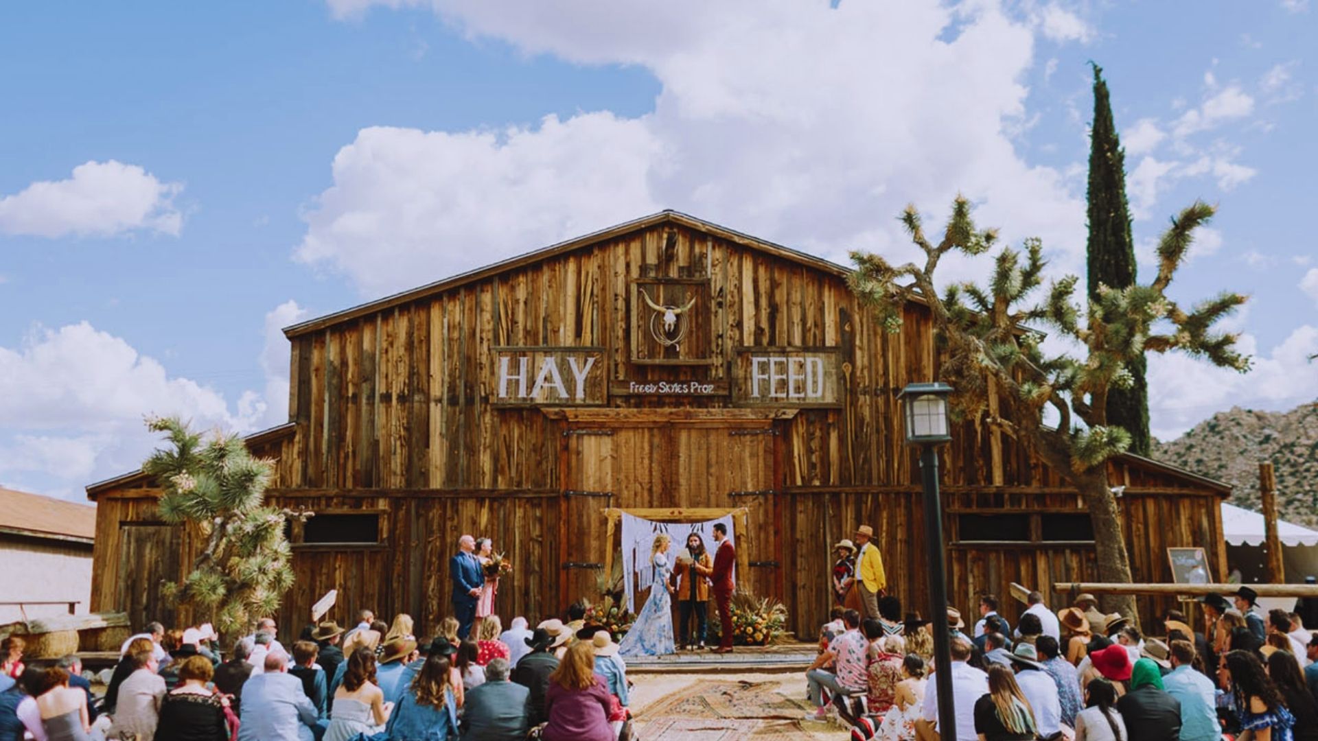 A picturesque wedding ceremony held in front of a barn, with attendees gathered and elegant decorations enhancing the scene.