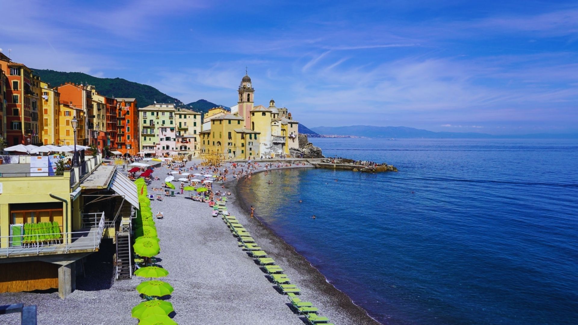 Vibrant beach in Italy featuring colorful buildings and people enjoying the sun and sea.