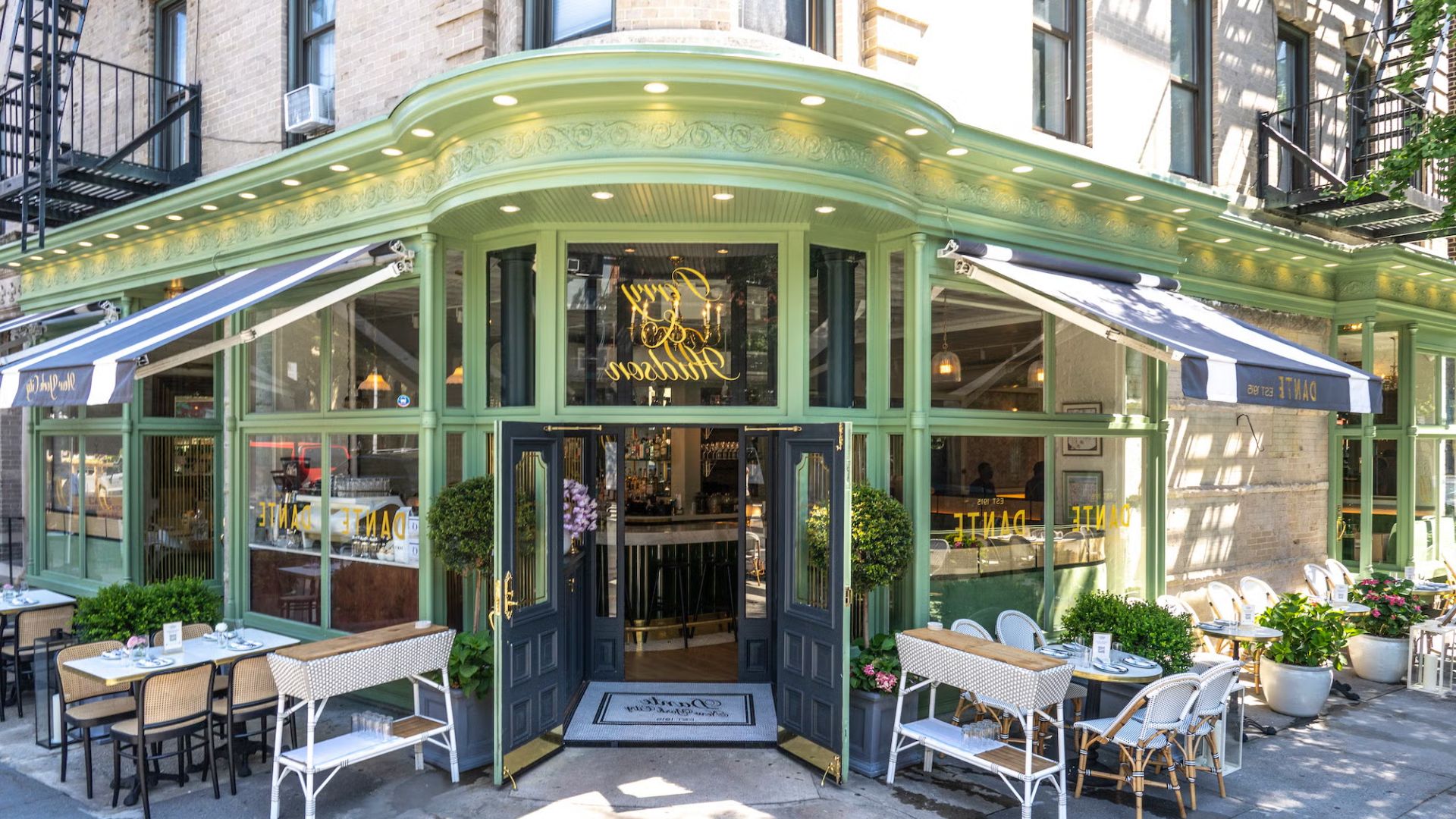 The exterior of a restaurant featuring outdoor tables and chairs arranged for dining.