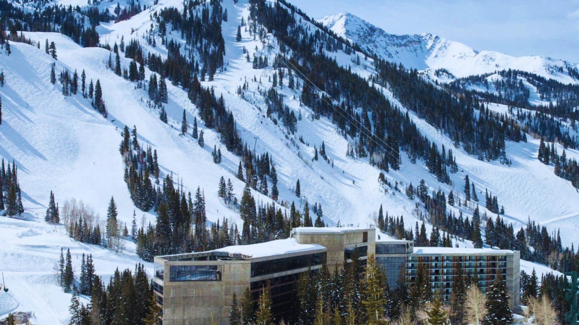 A ski resort with snow-covered slopes and a majestic mountain backdrop under a clear blue sky.