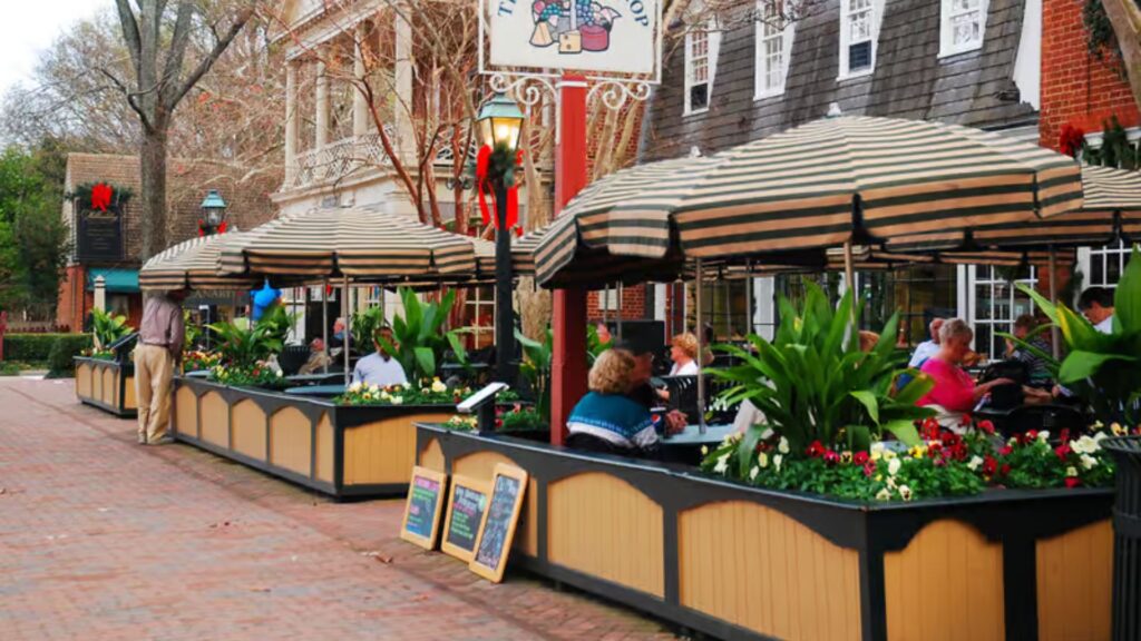 A brick sidewalk featuring tables with umbrellas, creating a cozy outdoor dining atmosphere.
