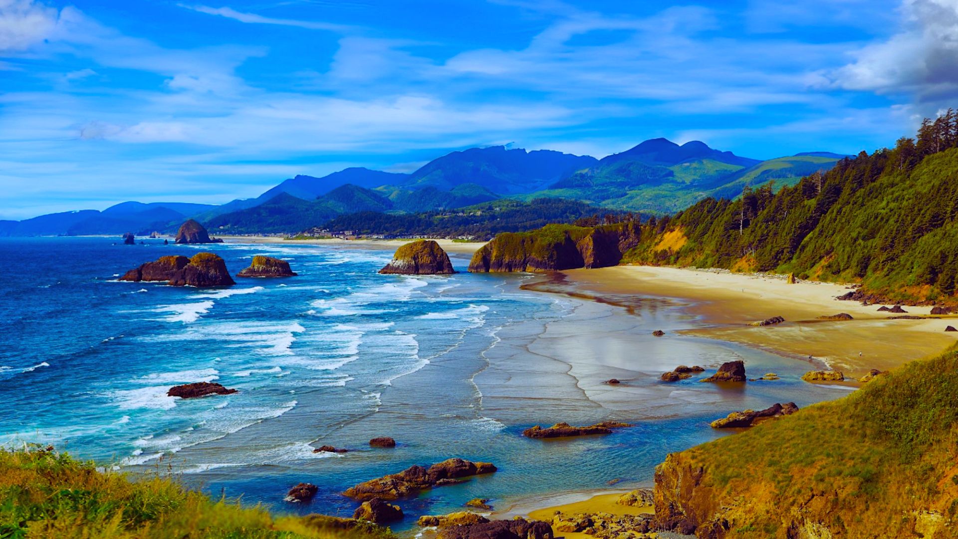 Scenic view of the ocean with waves crashing against the shore, framed by majestic mountains in the background.